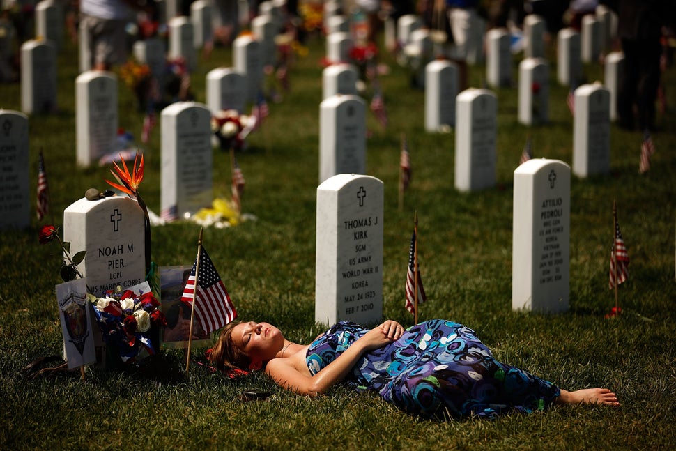 A young woman lays down on the grave of U.S. Marine Corps Lance Corporal Noah Pier on Memorial Day at Arlington National Ceme