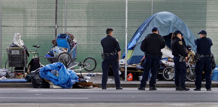 San Francisco police officers wait while homeless people collect their belongings Tuesday, March 1, 2016, in San Francisco. Crews in San Francisco have begun sweeping out a homeless camp under the city's Central Freeway.