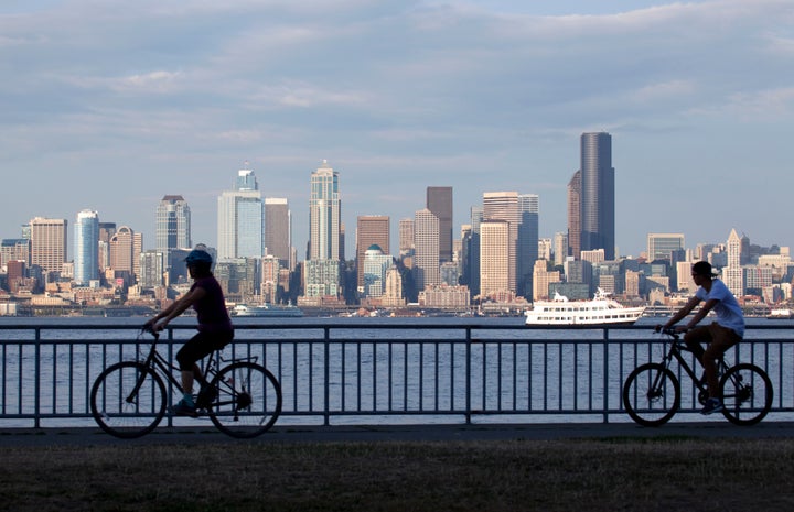 Cyclists bike near Elliot Bay, with Seattle in the background.