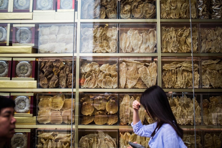 This March 29, 2016 photograph shows pedestrians walking past a display of different varieties of dried fish maw in a shopfront in Hong Kong.