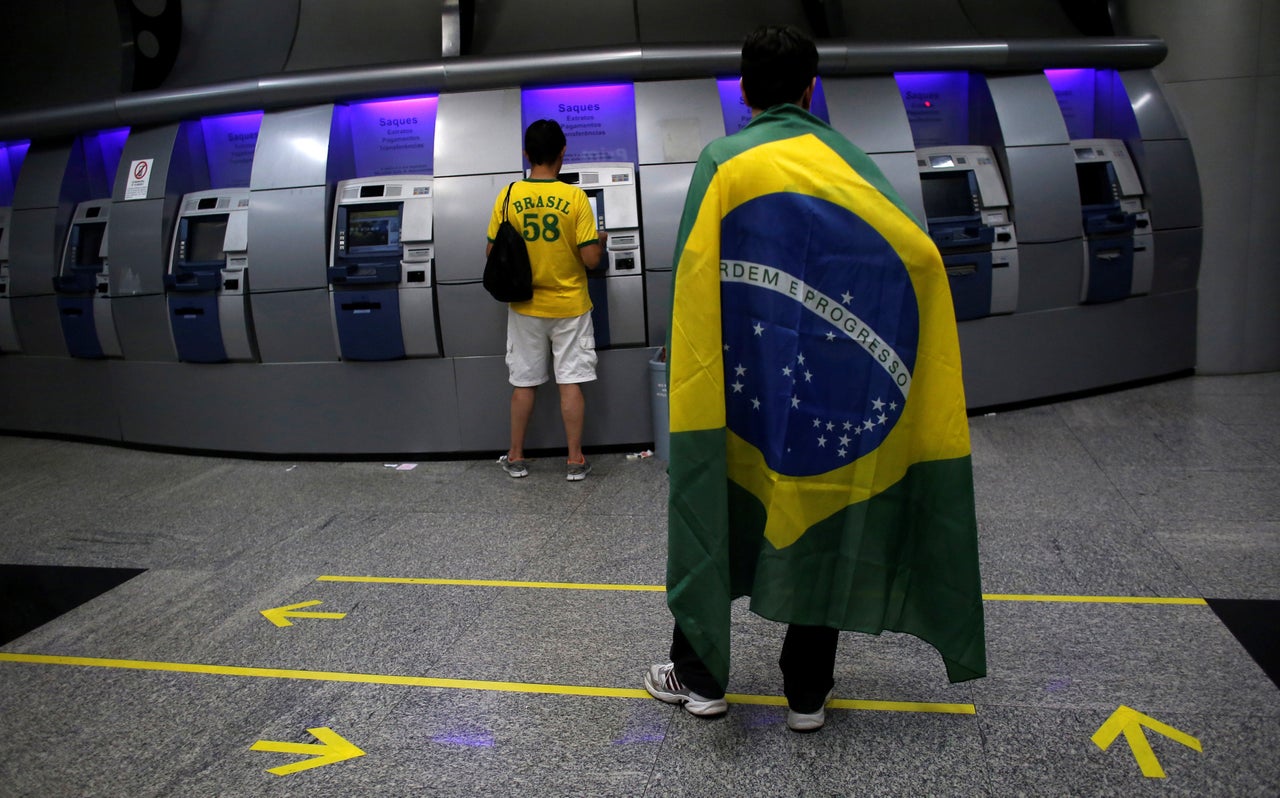 A man draped in the Brazilian flag waits inside the Banco do Brasil in Sao Paulo on March 15, 2015.