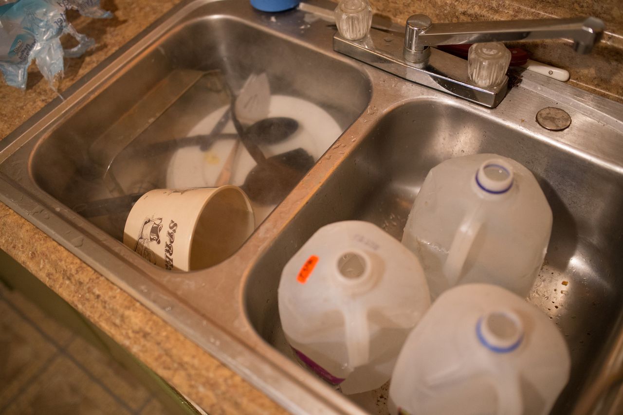 One side of the sink in this Flint home holds jugs filled with bottled water that a family can use to flush toilets. On the other side, bottled water that has been boiled for 45 minutes is used to wash dishes.