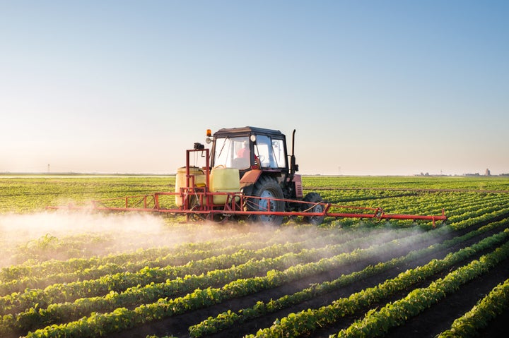 A tractor applies pesticides to a soybean field.