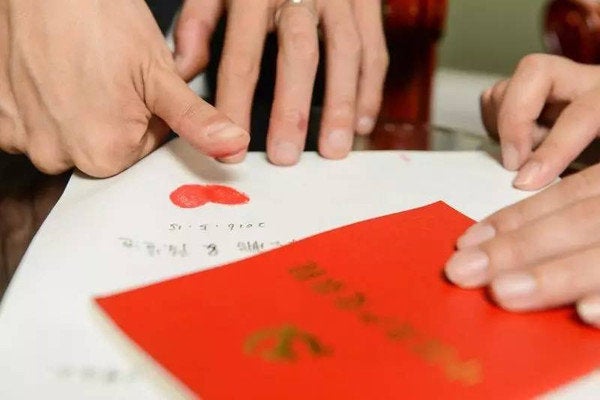 The newlyweds seal their transcription of the constitution with two red thumb prints in the shape of a heart.