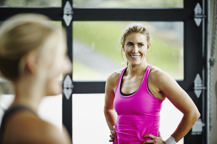 Smiling woman working out with friends in gym gym Thomas Barwick via Getty Images