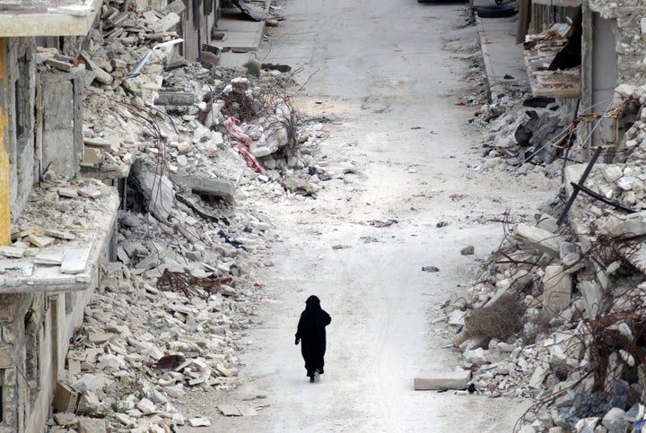 A woman walks past damaged buildings in Maaret al-Numan, a town in Syria's Idlib province. Women are still marginalized, says Reem Kanjo, a manager of the Women Now center, but she believes it is only a temporary phase.