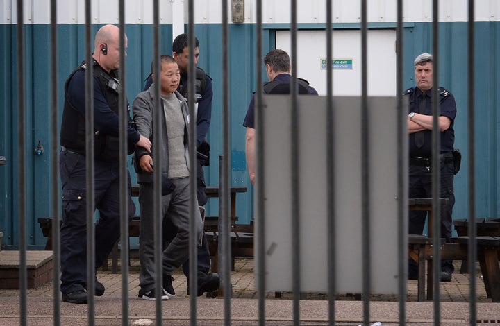 A man is led away by Border Force staff at Harwich International port in Essex last year after 68 people were found locked in a container.