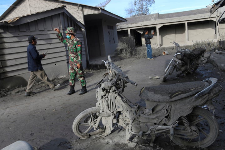An Indonesian soldier helps others search for survivors as the volcano continued to spew hot ash Sunday.