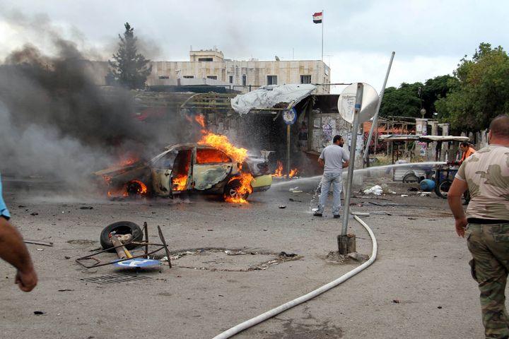 A firefighter tries to put out a fire from a burning car after explosions hit the Syrian city of Tartous, in this handout picture provided by SANA on May 23, 2016.