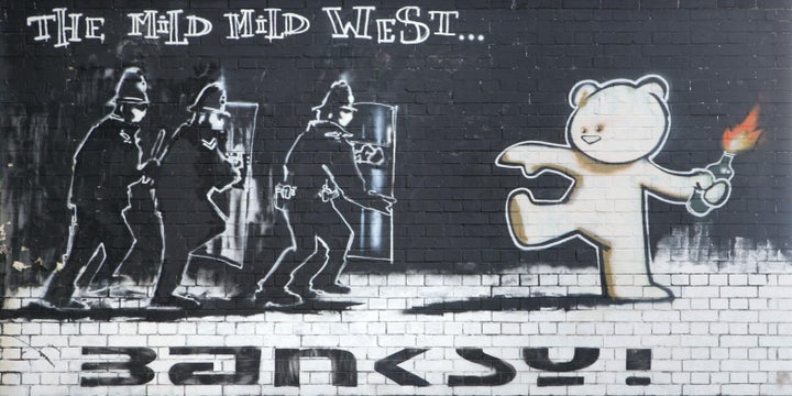 The "Kiss of Death" is located just yards away from Banksy's iconic "The Mild Mild West" in the Stokes Croft neighborhood of Bristol.