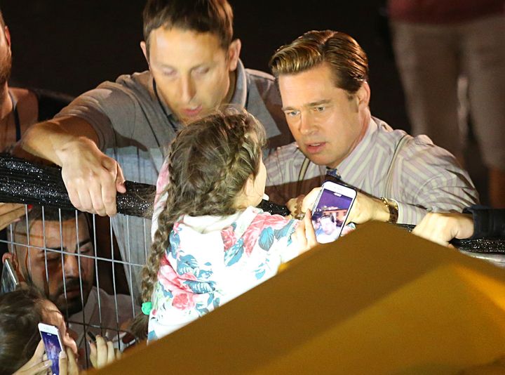Brad Pitt reaching out to help a young fan who was getting crushed by the crowd of people waiting to see him.