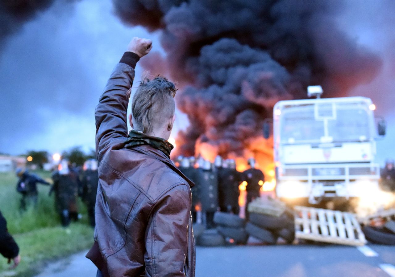 A protester raises his fist as riot police prepare to disperse refinery workers who are blockading the oil depot of Douchy-les-Mines, France, to protest the government's proposed labor reforms on Wednesday.