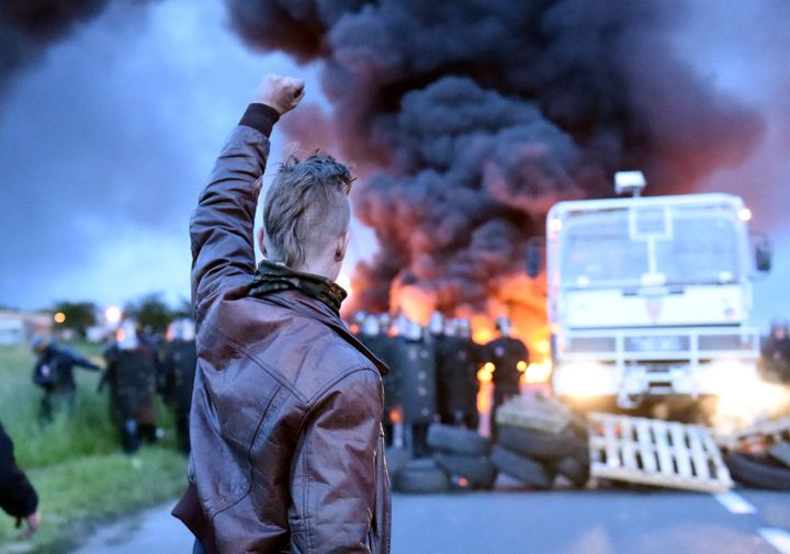 A protester raises his fist as riot police prepare to disperse refinery workers who are blockading the oil depot of Douchy-les-Mines, France, to protest the government's proposed labor reforms on Wednesday.