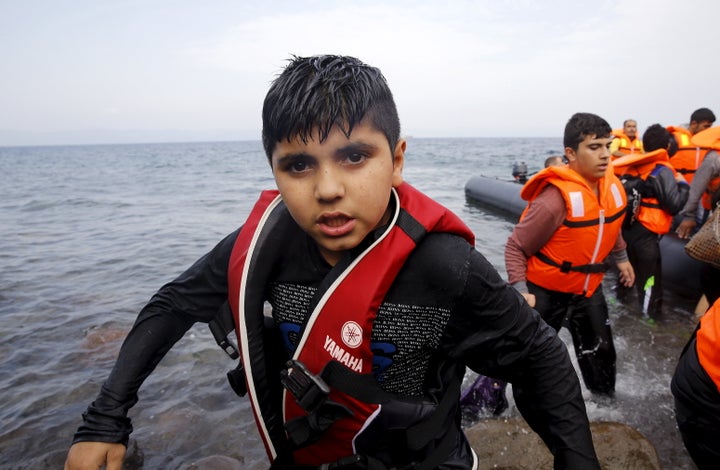 A Syrian refugee boy desembarks from a raft at a beach on the Greek island of Lesbos after crossing a part of the Aegean Sea