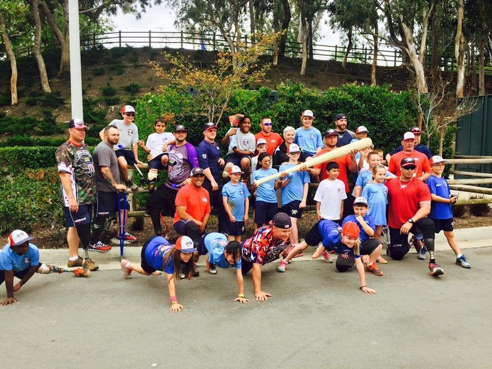 Ferreira and The Wounded Warriors Amputee Softball Team poses with children who have had limbs amputated.