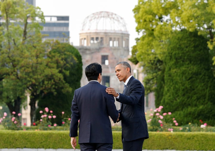President Barack Obama puts his arm around Japanese Prime Minister Shinzo Abe after they laid wreaths in front of a cenotaph