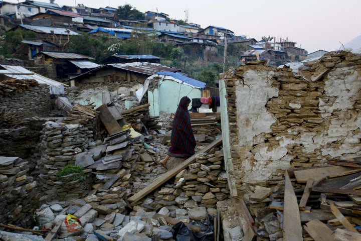 A Nepalese woman still searches her belongings on the debris of her destructed house in Barpak of the Gorkha District, Nepal,