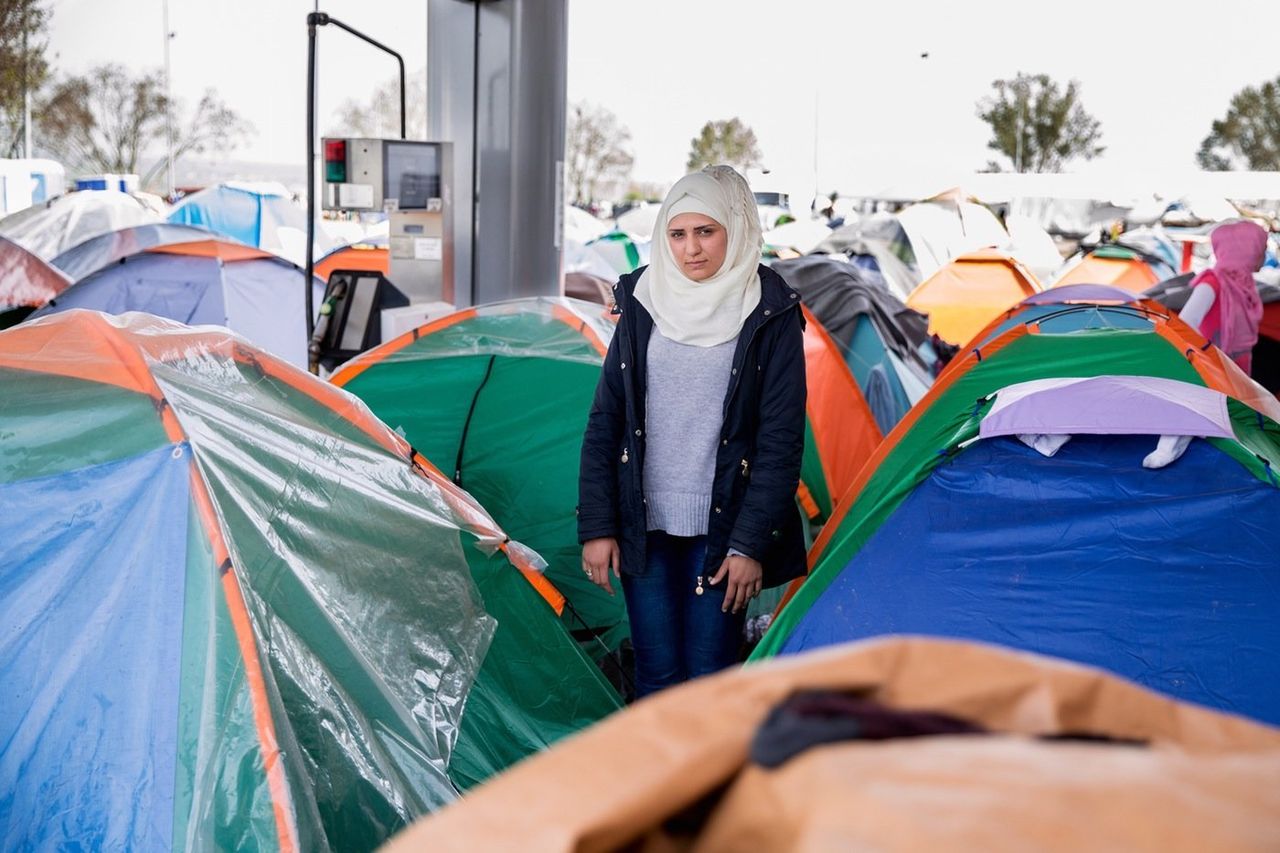 Rahaf Habash, 21, stands next to her small tent near a crowded gas pump. She was married to her husband Basel for fewer than four months when he left their home outside Damascus for Germany. She later followed him in February and was forced to give up most of her belongings and valuables as bribes, including her wedding ring. 