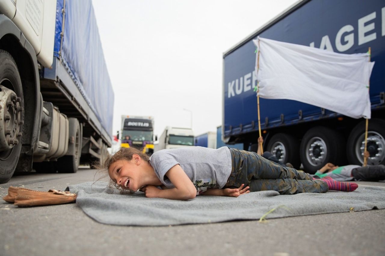Heleen, 11, from Qamishli, Syria, lays across the highway in protest against closed borders on April 2, 2016. "If the border opens, we will go," she says. 