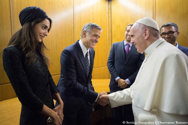 George Clooney, with his wife, Amal, shakes the hand of Pope Francis during Sunday's meeting.