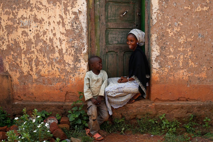 The future of the radio station in this fragile country remains precarious. Above, a woman and a boy sit outside their house in Bambari in June 2014.