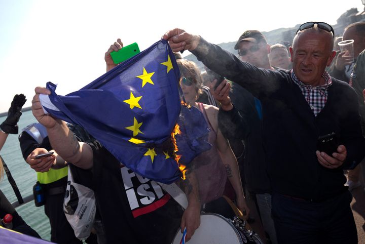 A group of far-right protesters burn an EU flag after a demonstration in Dover on Saturday