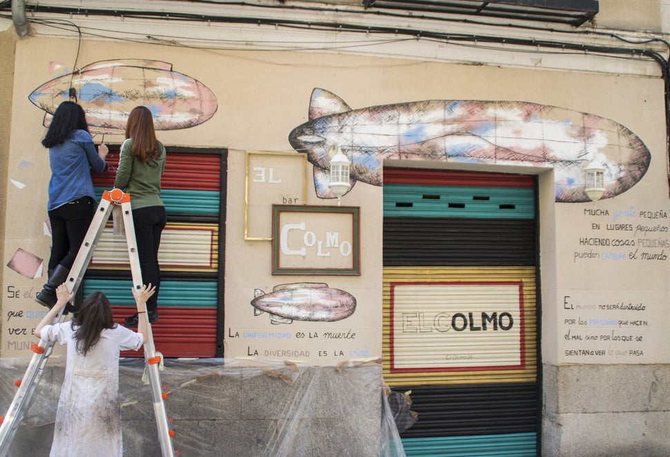 Artists cover the facade of the bar El colmo with illustrations of zeppelins, books, and quotes by the likes of Victor Hugo,