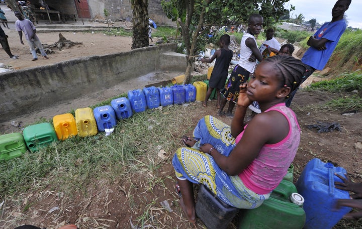 A girl sits on a canister while other locals wait to collect drinking water on August 10, 2010 in Abobo, a poor neighborhood in Abidjan. Women from various parts of the country's economic capital often spend the night queueing in the hope that they will be able to get potable water. AFP PHOTO/ISSOUF SANOGO (Photo credit should read ISSOUF SANOGO/AFP/Getty Images)