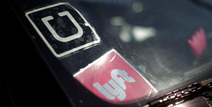 A driver displays Uber and Lyft ride-hailing signs in his car windscreen in Santa Monica, California, May 23, 2016.
