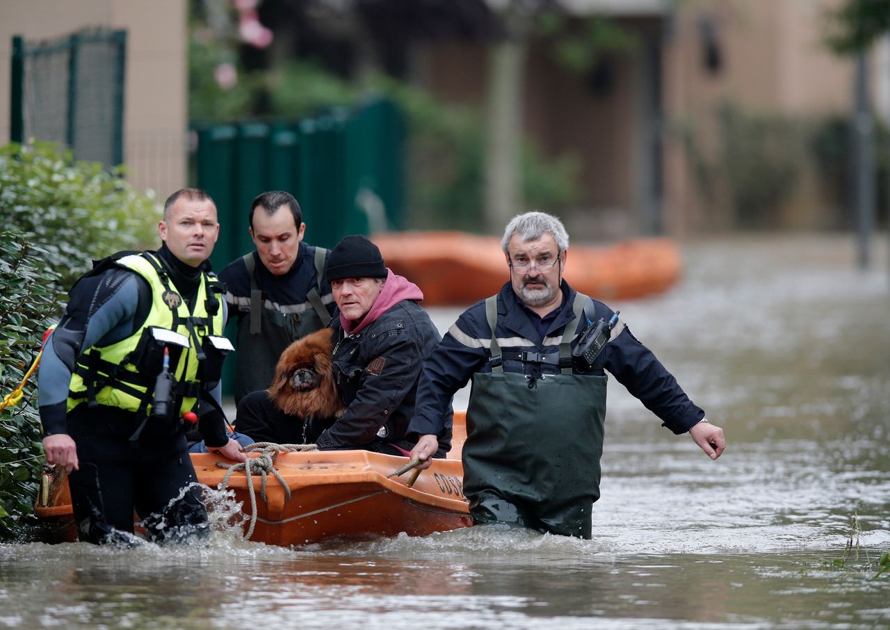 French firefighters evacuate residents, with a dog in tow, from a flooded area in Longjumeau, Paris, after days of almost nonstop rain caused flooding in the country.