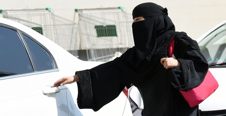 A Saudi woman gets into a taxi at a mall in Riyadh, Saudi Arabia.