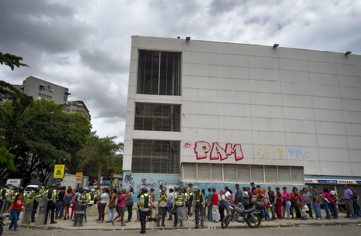 Police stand guard as people line up outside a supermarket in Caracas on June 1, 2016. Basic consumer products, including food and medicine, are now in short supply in Venezuela.