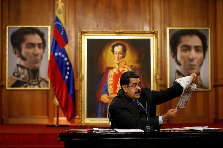 Venezuelan President Nicolás Maduro holds a copy of a newspaper as he speaks in front of images of South American hero Simón Bolívar during a news conference at Miraflores Palace in Caracas, Venezuela, on May 17, 2016.