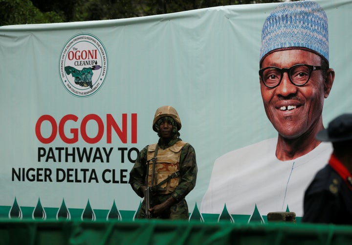 A soldier stands guard in front of a banner with a picture of Nigeria's President Muhammadu Buhari in Gokana during the launch of a major oil cleanup initiative. It is expected to take 25 years.