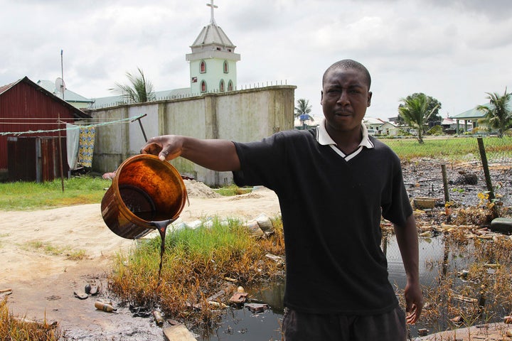 A man shows a bucket of crude oil spilled after a Shell pipeline leaked in the Oloma community of Nigeria's Delta region in 2014. Hundreds of oil spills each year caused catastrophic damage to the wetlands region.