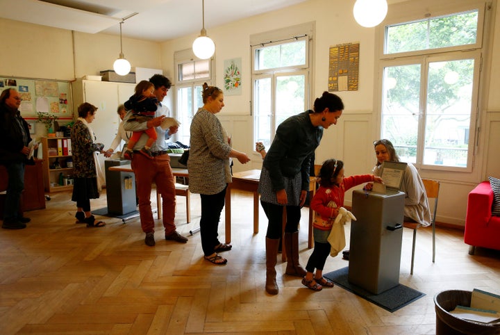 People cast their ballots during a vote on whether to give every adult citizen a basic guaranteed monthly income of 2,500 Swiss francs ($2,560), in a school in Bern, Switzerland, June 5, 2016.