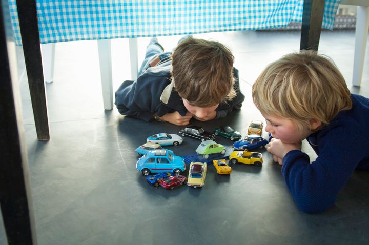 children playing with their cars under the table Mieke Dalle via Getty Images