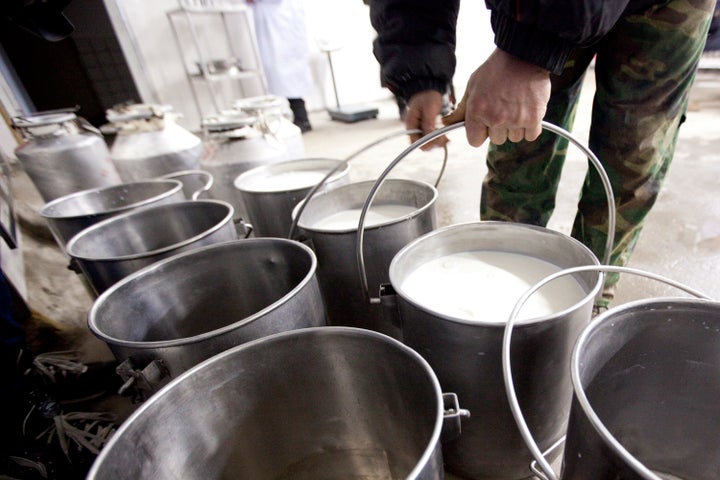 A dairy farmer moves buckets of raw milk at a Nestle SA milk collection center in Shuangcheng, Heilongjiang Province, China,