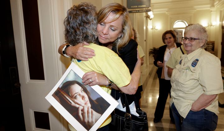 Debbie Ziegler holds a photo of her daughter, Brittany Maynard, and get a hug after the California legislature approved the End of Life Option Act last year.