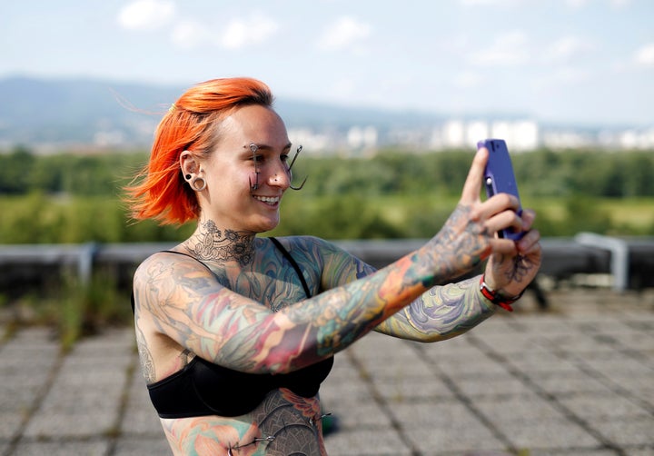 Kaitlin, 28, from the United States takes a selfie as she waits to be suspended by the professional body artist Dino Helvida.