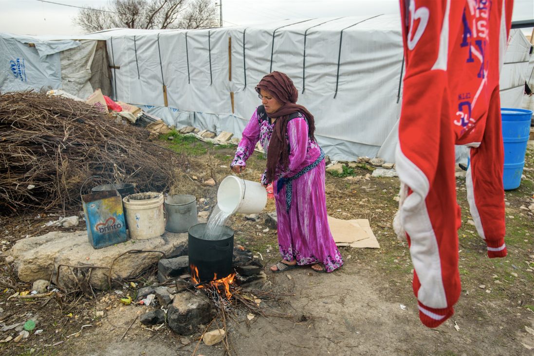 Woman preparing a pot of boiling water for laundry, in the Bekaa Valley, Lebanon.