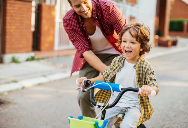 Photo of a little boy learning how to ride bicycle with a help of his father Geber86 via Getty Images