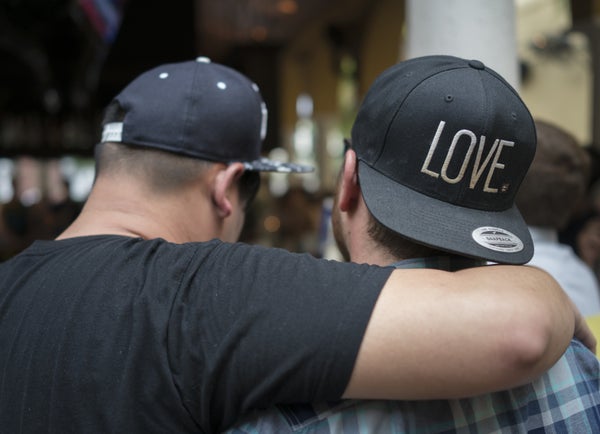 Men console each other at a Ember Restaurant in Orlando as new reports come over the TV about the shooting at the Pulse night