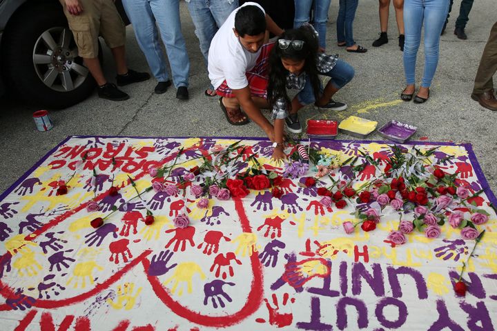 A man helps a girl put handprints on a makeshift memorial on the ground near Pulse nightclub.