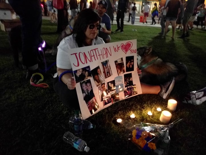 Francesca Garcia sits with a poster adorned with photos of her friend Jonathan Camuy, who died during Sunday's shooting. 