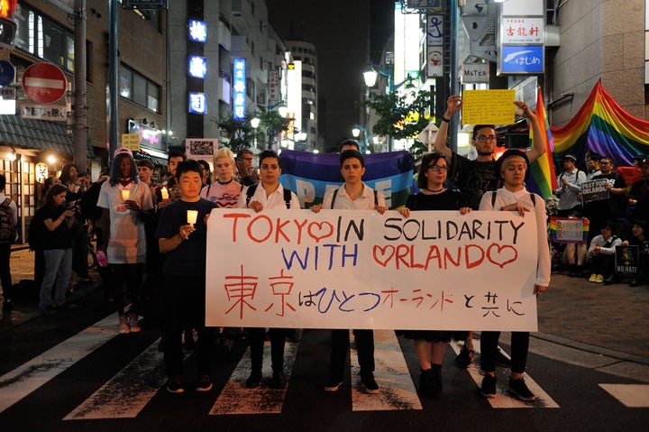 People carrying banners and candles paid tribute to victims of Sunday's mass shooting in a Tokyo, Japan, neighborhood on Tuesday.