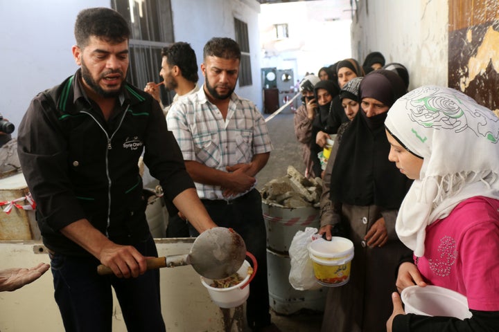 An NGO worker serves food to impoverished Syrian families during the Muslim holy fasting month of Ramadan on June 11, 2016, in a rebel-held neighborhood of the northern city of Aleppo.