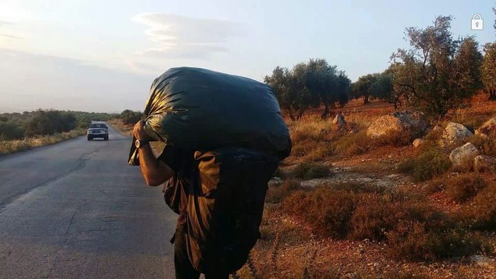 Adham walks into Aleppo with hundreds of toys on his back.