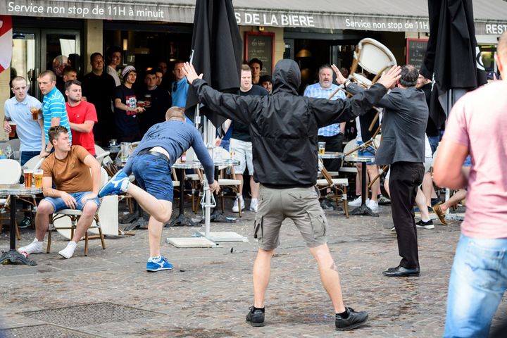 A man throws a chair as a small group of Russian men provoke a group of England supporters in the centre of Lille