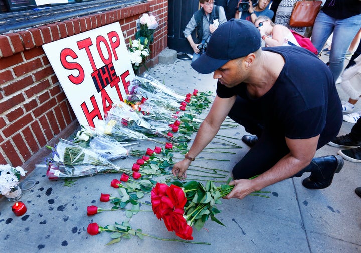 "Stop the Hate," reads a sign outside the Stonewall Inn in New York City on Sunday. Nearby, people gathered to honor the victims of the Orlando massacre.